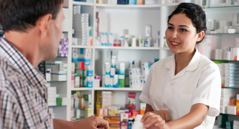 Female pharmacist passing some tablets to a man