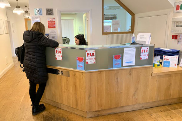 Lady stood at reception asking receptionist a question
