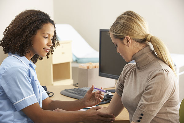 Nurse injecting a lady in the arm